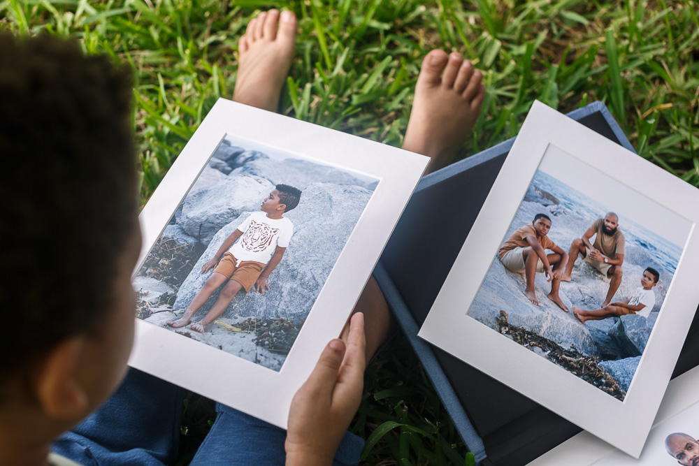 Little boy holding and looking at photos of himself with his family.